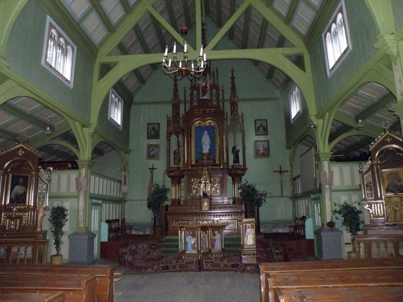 Wnętrze starszego drewnianego kościoła - w głębi neogotycki, drewniany ołtarz główny z figurą Matki Boskiej Uzdrowienia Chorych